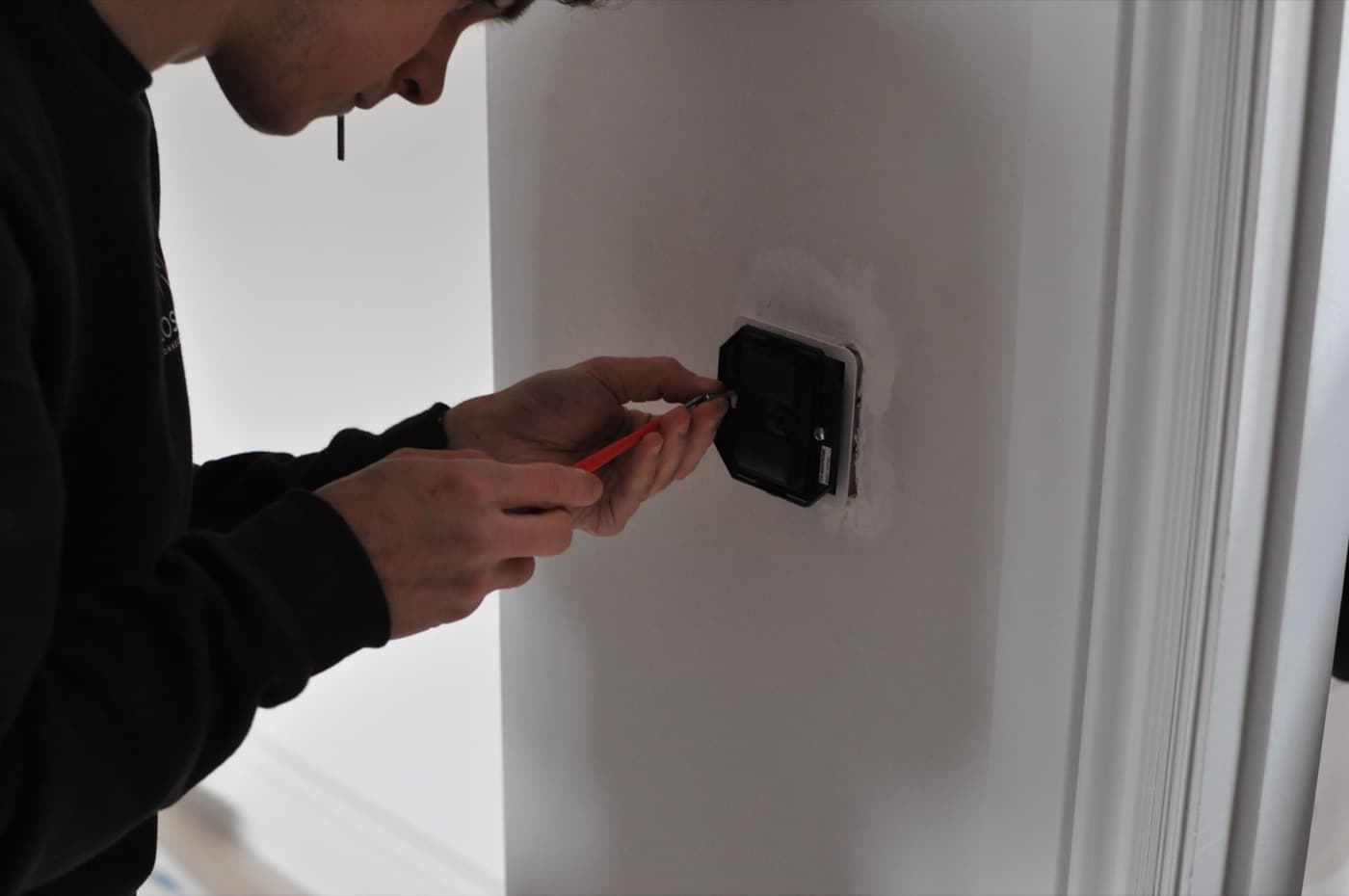An electrician fitting a switch module into a plastered wall